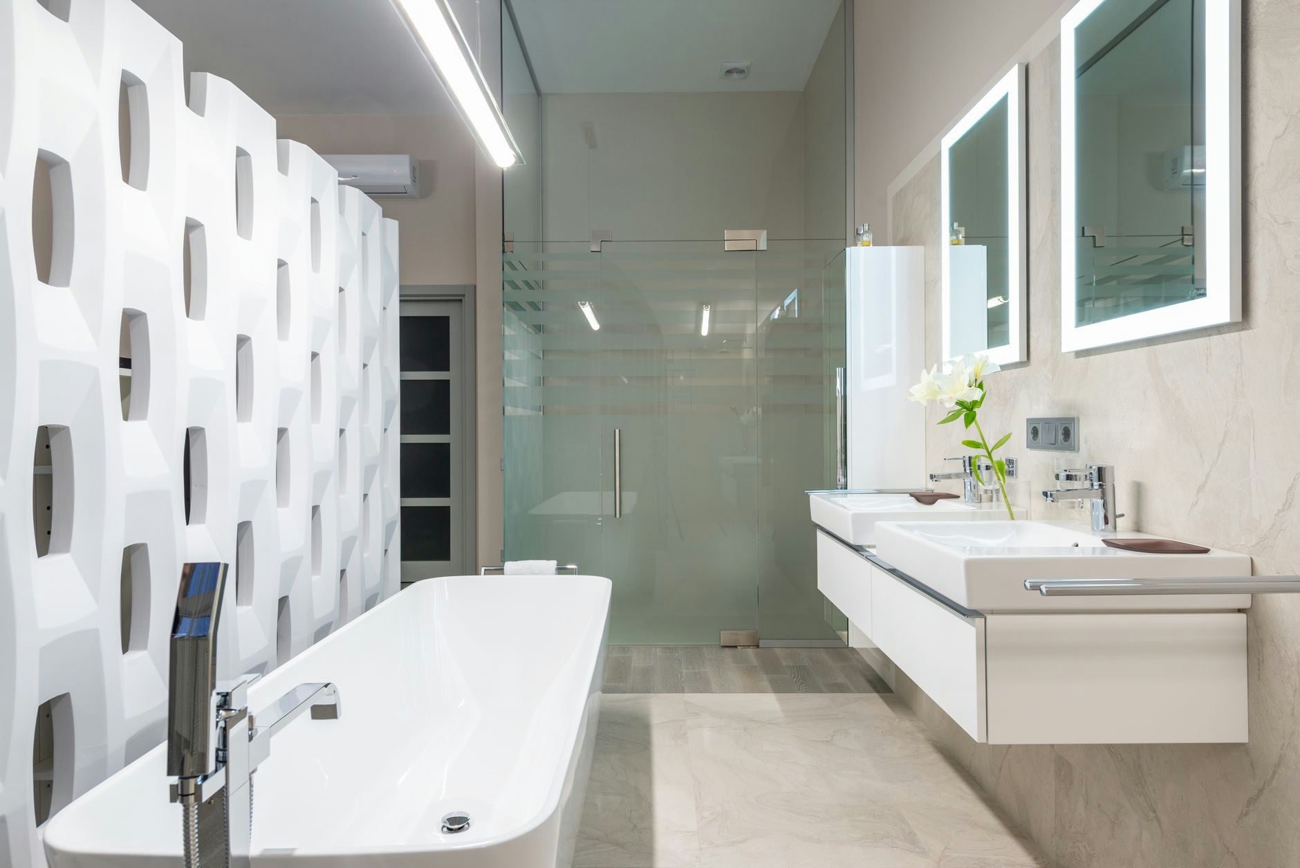 White bathtub with tap near decorative partition placed near sink and mirrors in stylish light bathroom with glass shower cabin